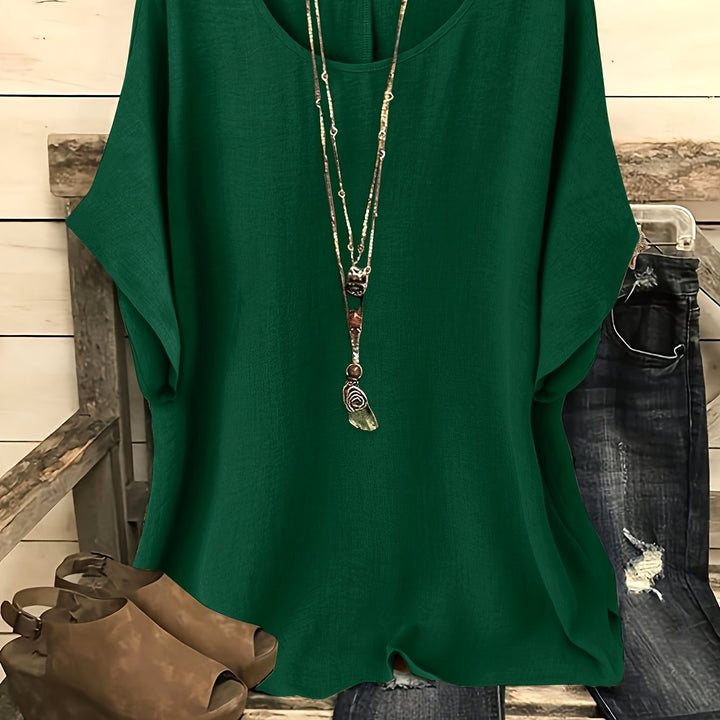 Dark green linen-look top with a round neck and relaxed batwing sleeves, styled with a layered necklace.