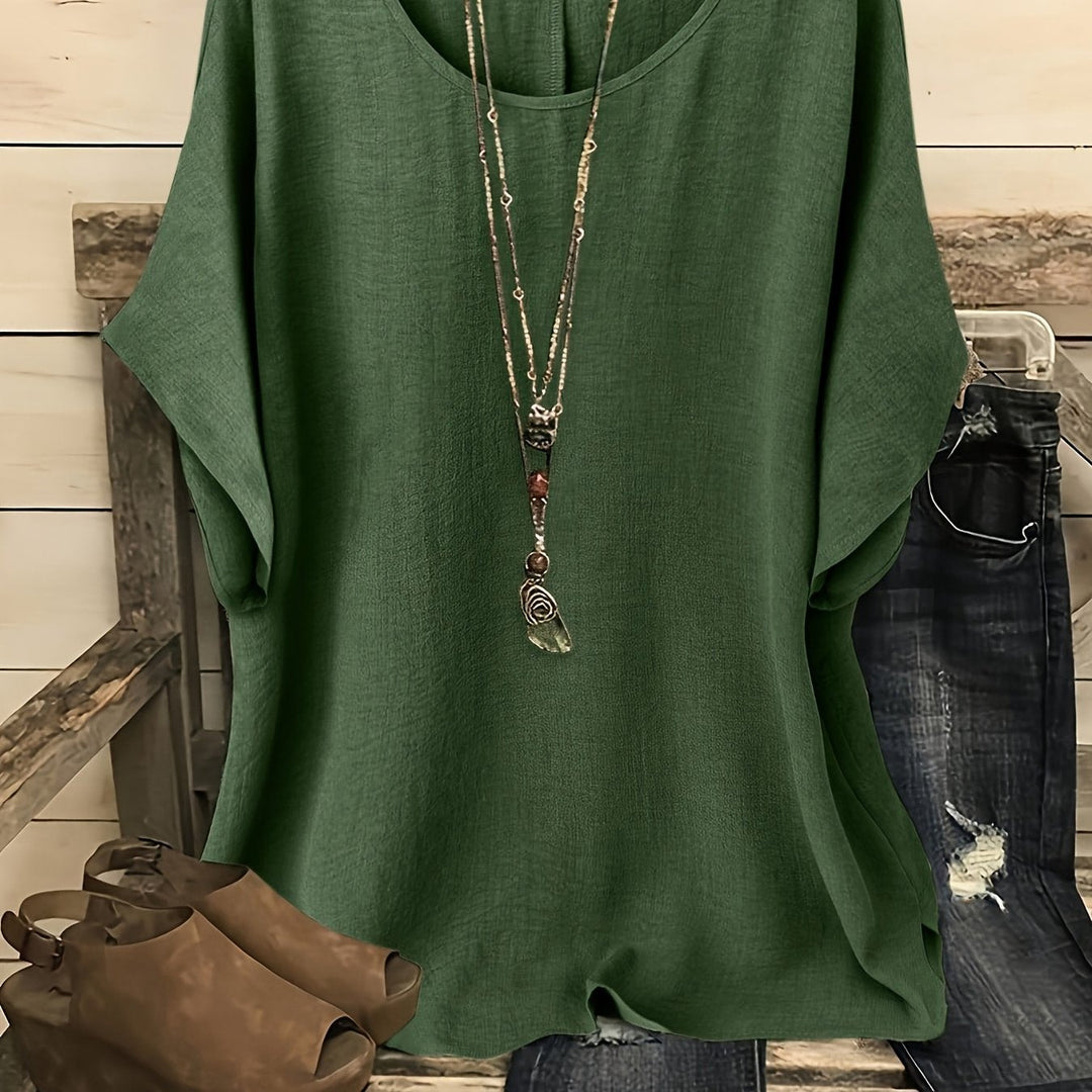 Relaxed forest green linen-look top with a round neck and batwing sleeves, styled with a layered pendant necklace.