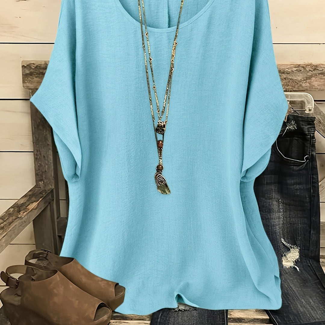 Light blue linen-look round neck top with batwing sleeves, styled with a layered pendant necklace.