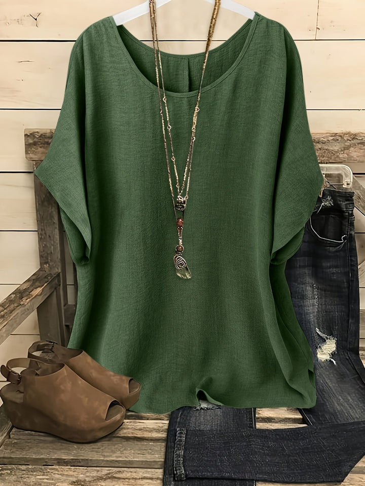 Relaxed forest green linen-look top with a round neck and batwing sleeves, styled with a layered pendant necklace.