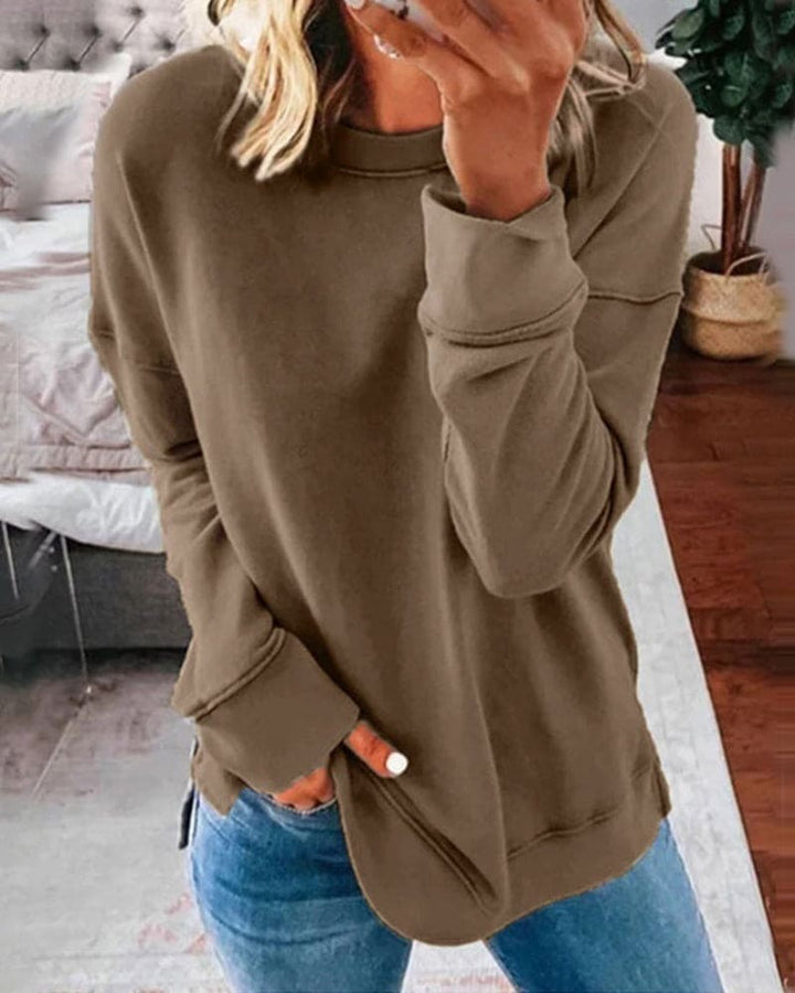 Brown crew neck long sleeve sweatshirt with a relaxed fit, ribbed cuffs, and side hem slits worn with blue jeans.