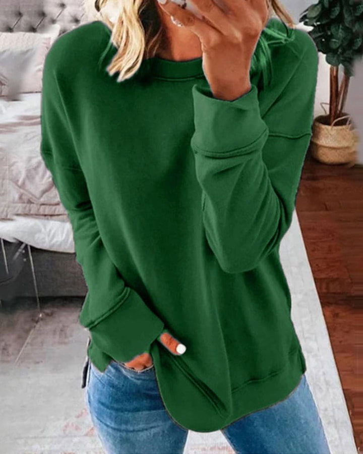 Forest green long-sleeve crew neck sweatshirt with a relaxed fit, ribbed cuffs, and side hem slits worn with jeans.