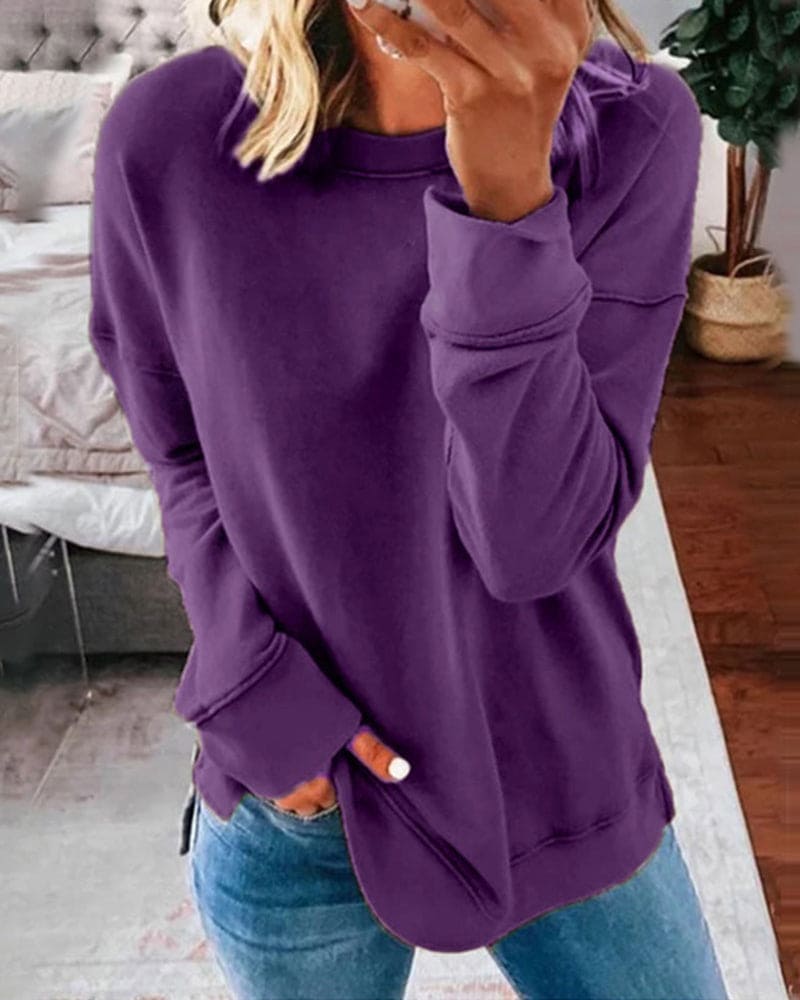 Purple long-sleeve crew neck sweatshirt with a relaxed fit, ribbed cuffs, and side hem slits worn with blue jeans.