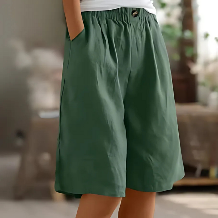 Maisie women's dark green elastic waist Bermuda shorts with pockets and a single button closure.