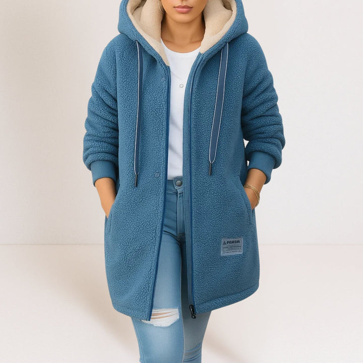 Blue longline sherpa fleece jacket with a cream-lined hood, full-length zip, and side pockets.