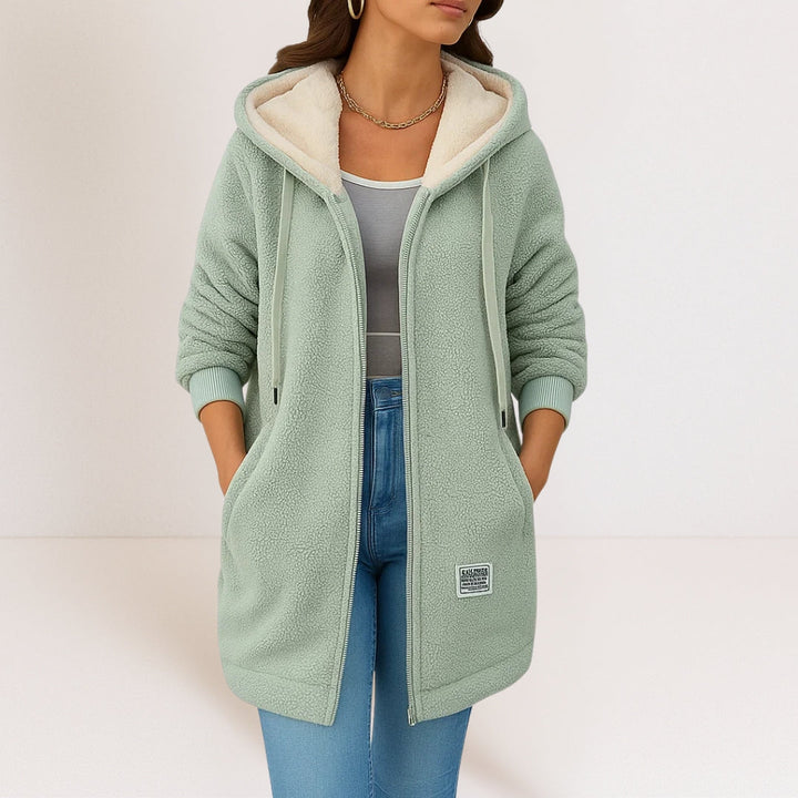 Sage green longline sherpa fleece jacket with a cream-lined hood, full-length zip, and side pockets.