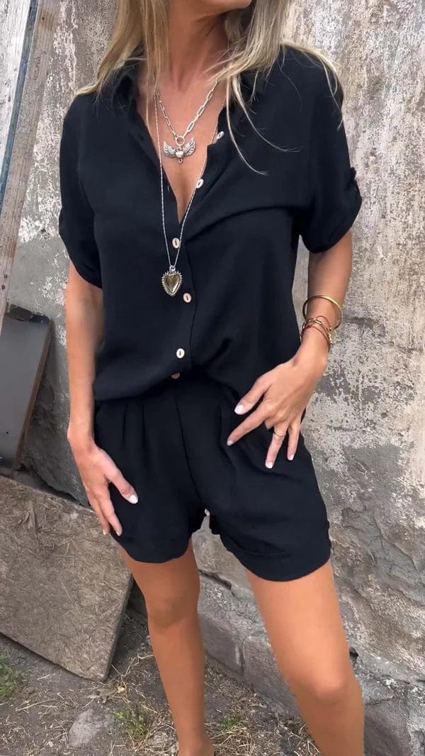 Woman wearing a black linen-look two-piece set with a collared button-up shirt and matching pleated shorts.