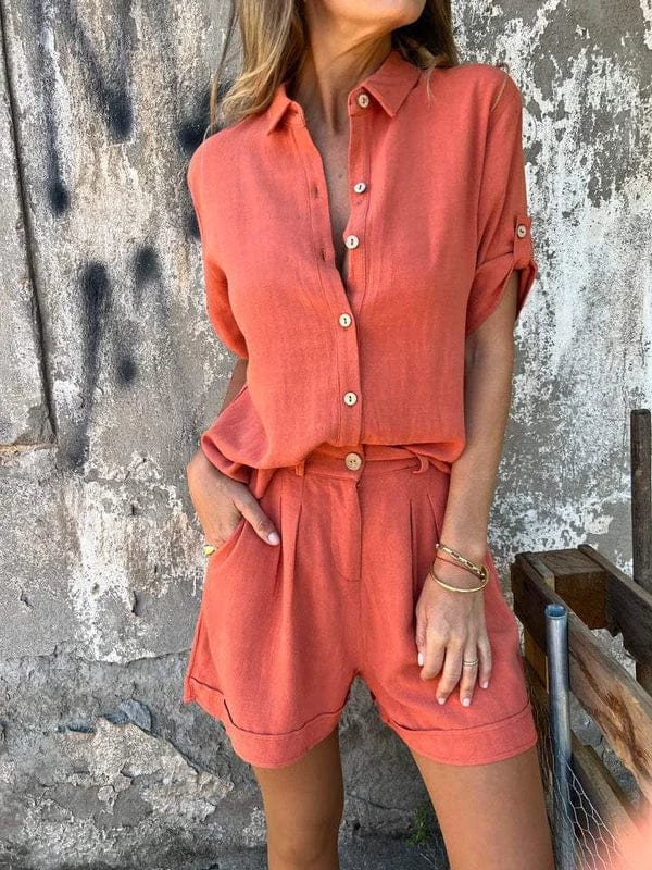 Woman wearing a terracotta linen-blend set featuring a collared button-up shirt with roll-up sleeves and pleated shorts with pockets.