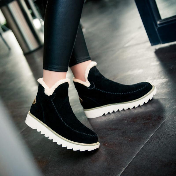 Black suede-look ankle boots featuring a plush faux fur cuff, moccasin stitching, and a white grippy ribbed sole.