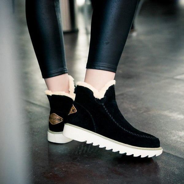 Black suede-look ankle boots with plush faux fur trim, slip-on design, and a durable white ribbed sole for winter comfort.