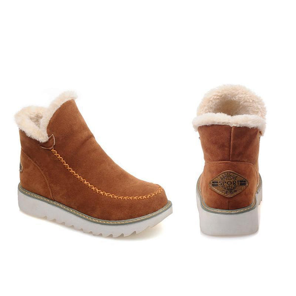 Tan suede-look ankle boots with plush faux fur trim, decorative moccasin stitching, and a grippy white ribbed sole.