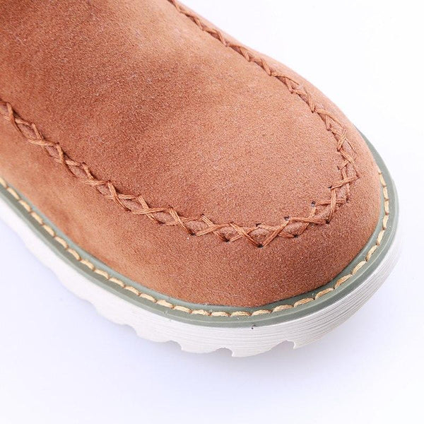 Tan suede-look ankle boot featuring moccasin-style stitching and a durable, grippy white ribbed sole.