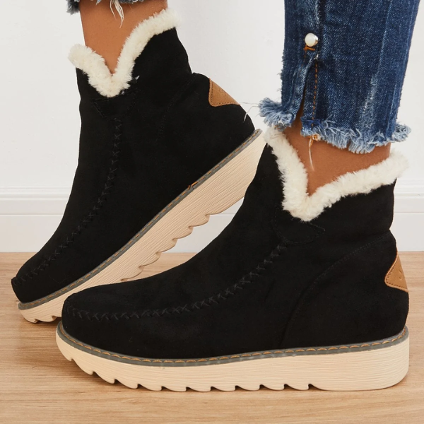 Black suede-look ankle boots featuring a plush faux fur cuff, moccasin stitching, and a sturdy, grippy ribbed sole.