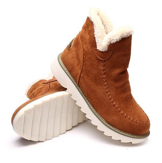 Tan suede-look ankle boots with plush faux fur trim, moccasin stitching, and a white grippy ribbed sole for cosy winter style.