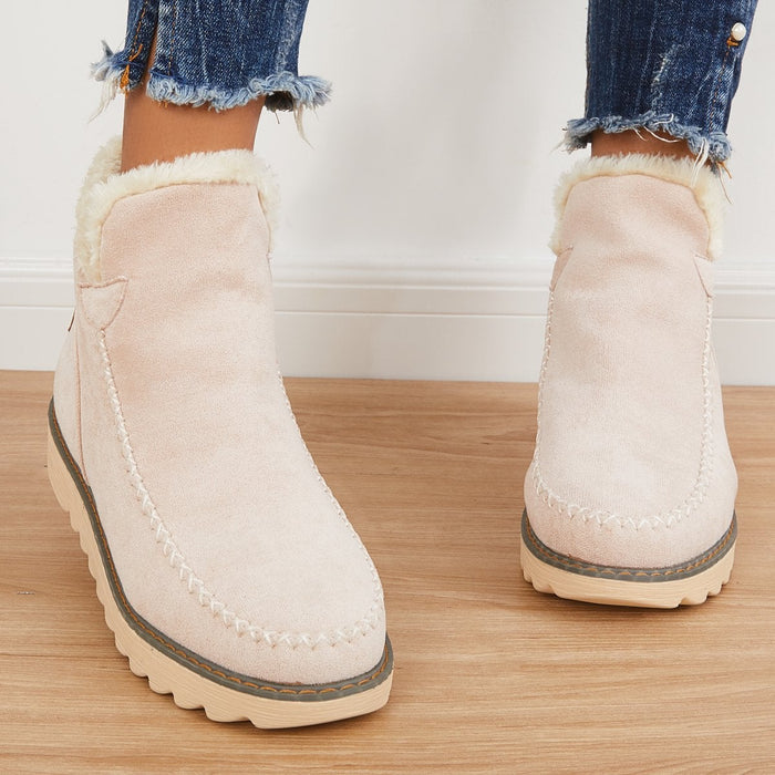 Beige suede-look ankle boots with plush faux fur cuffs, moccasin stitching, and a grippy ribbed sole for winter comfort.