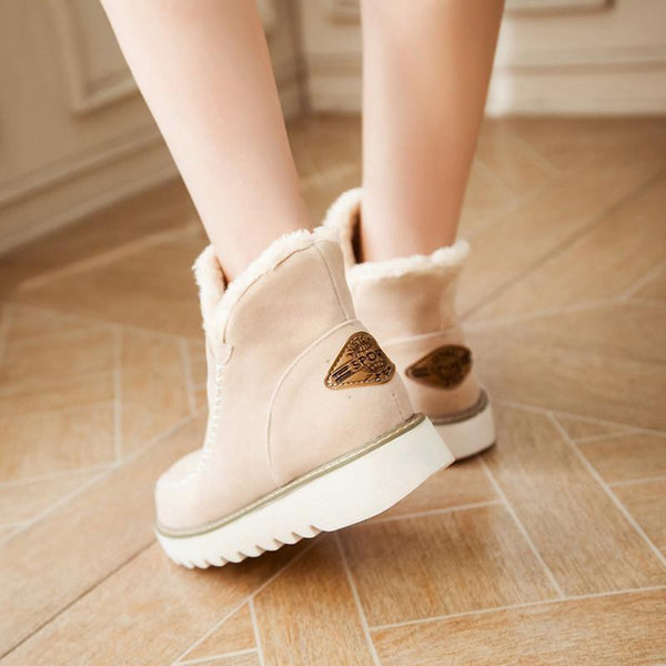 Beige suede-look ankle boots featuring a plush faux fur cuff, moccasin stitching, and a durable white ribbed sole.
