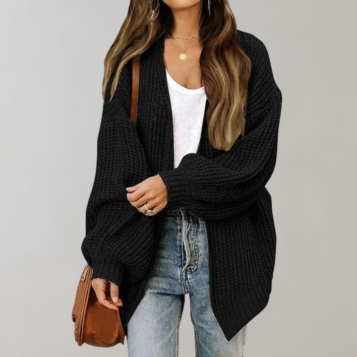 Black chunky knit oversized cardigan with an open front, relaxed balloon sleeves, and ribbed cuffs worn over jeans.