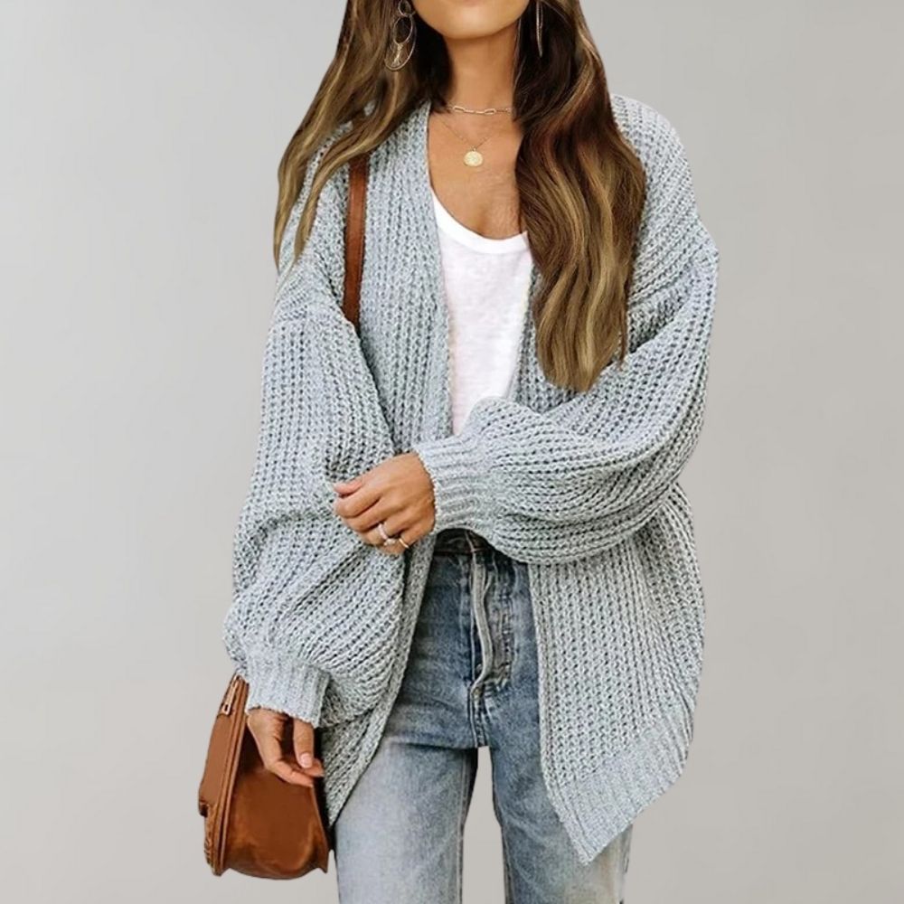Light blue chunky knit oversized cardigan with an open front and balloon sleeves worn over a white tee and jeans.