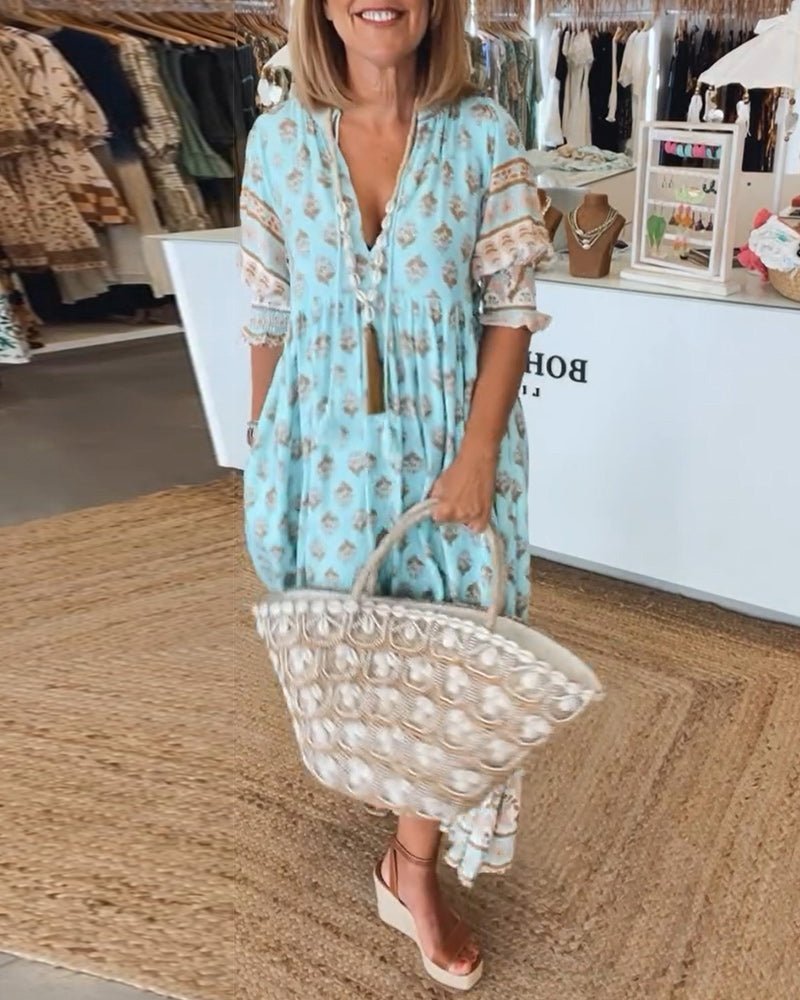 Women's Matilda floral V-neck maxi dress in light blue with brown print, flowing fabric, and tassel ties.