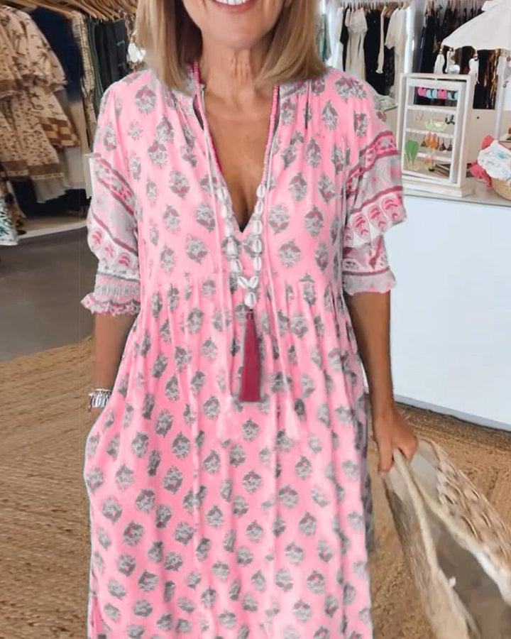 Matilda floral V-neck maxi dress in light, fluid pink fabric with grey print and tassel details.