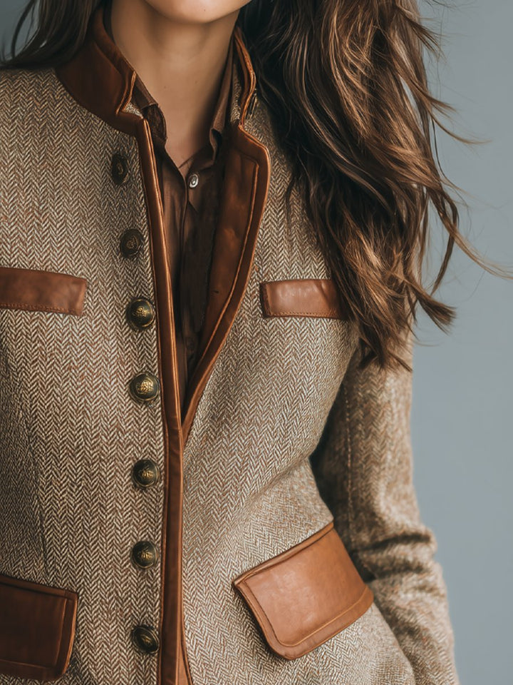 Tailored herringbone tweed blazer with brown leather-look trim, antique brass buttons, and a structured band collar.