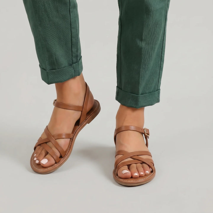 Brown sandals worn with green pants on a neutral background