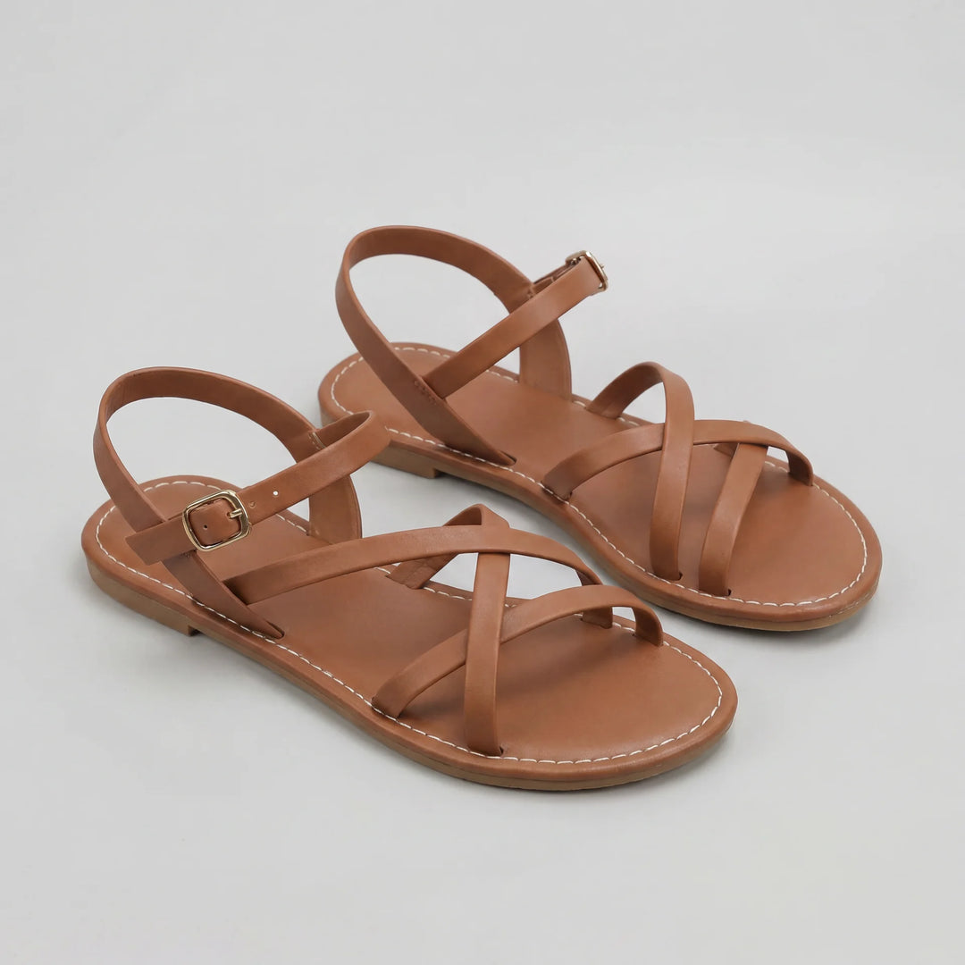 Pair of brown sandals with criss-cross straps on a light gray background