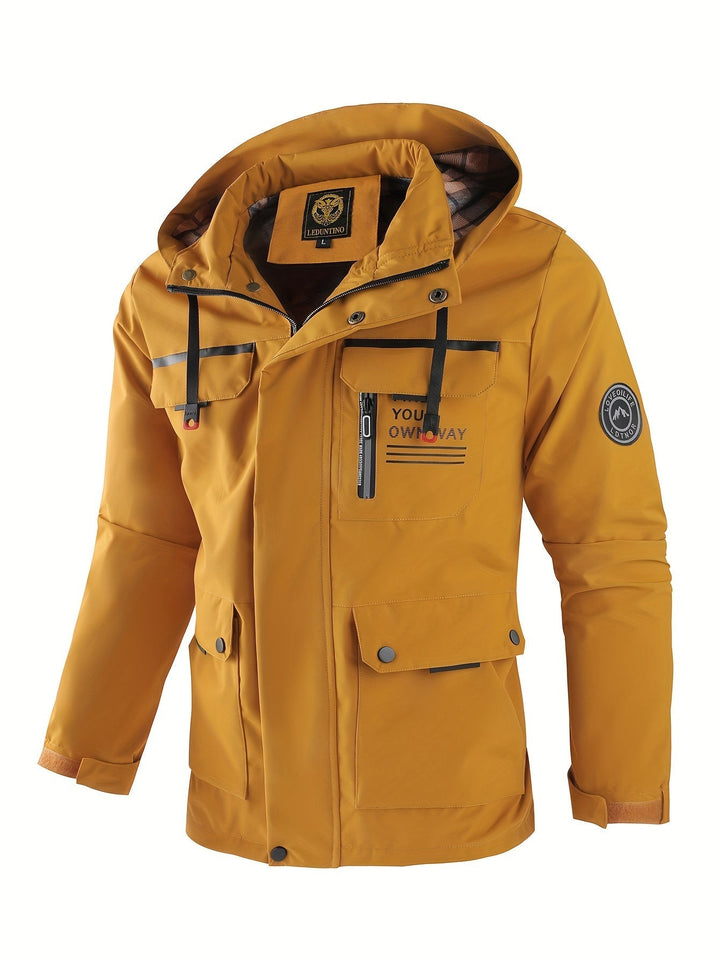 Mustard yellow men's utility jacket with a hood, multiple flap pockets, full-length zip, and branded sleeve patch.