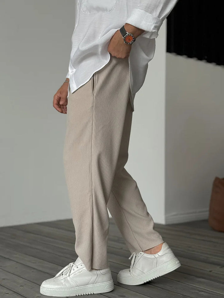 Beige men's tapered trousers in a soft vertical ribbed fabric with an elasticated waist and relaxed fit.