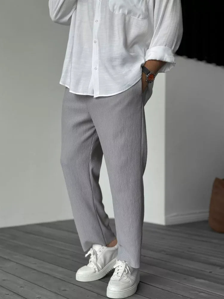 Men wearing grey tapered trousers with a vertical ribbed texture, elasticated waist, and white sneakers.