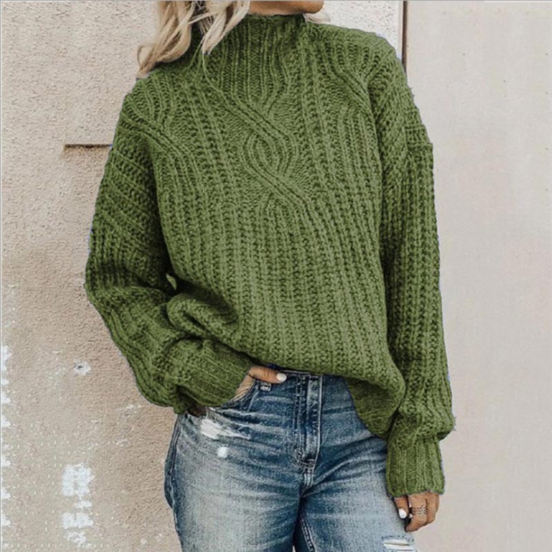 Olive green chunky cable-knit jumper with a mock neck and relaxed fit worn with blue jeans.