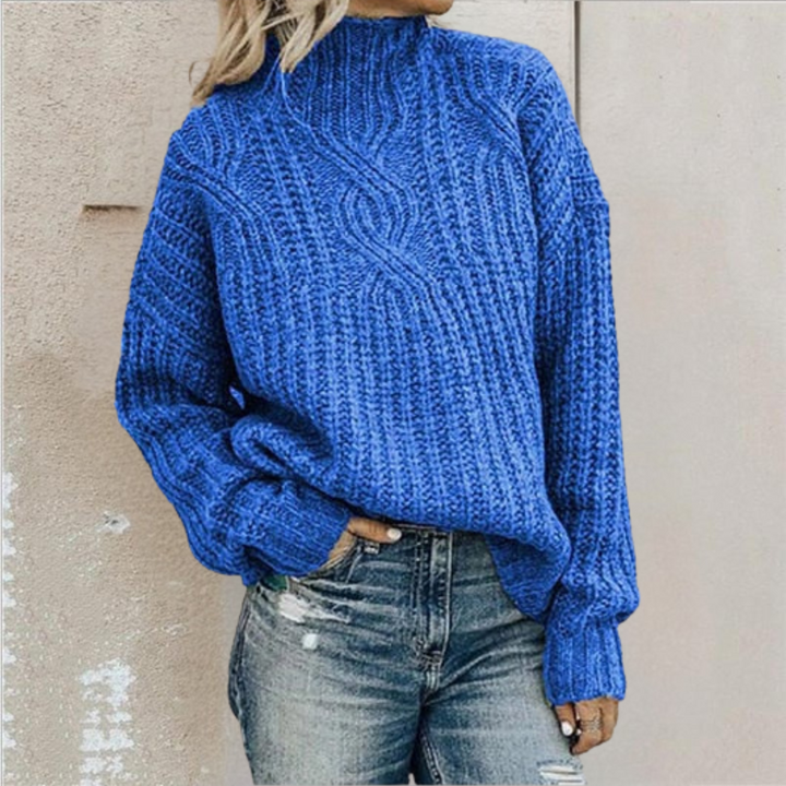 Bright blue cable-knit jumper with a mock neck and relaxed fit, paired with distressed blue jeans.