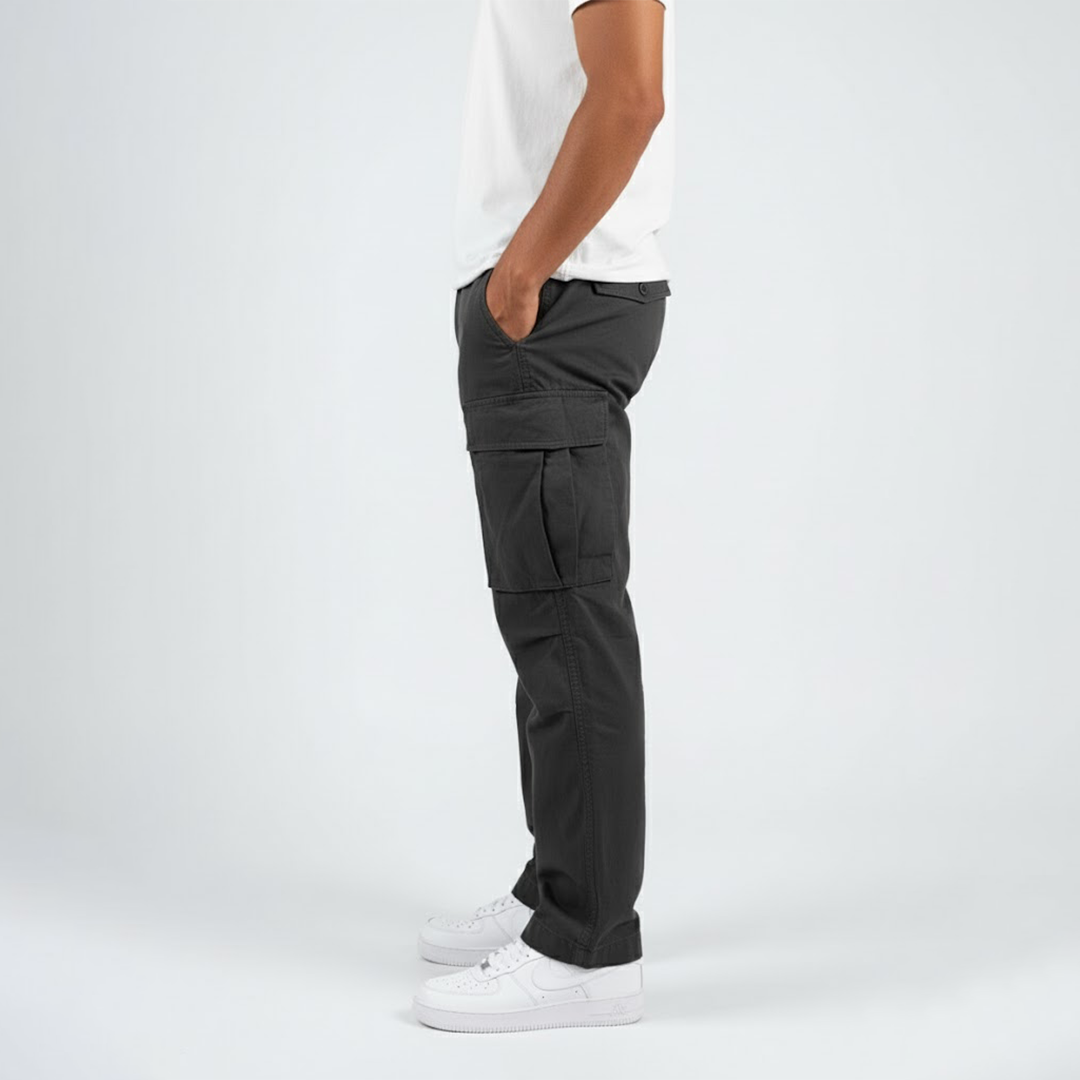 Side profile of men's charcoal grey relaxed-fit cotton cargo trousers with side pockets and white sneakers.