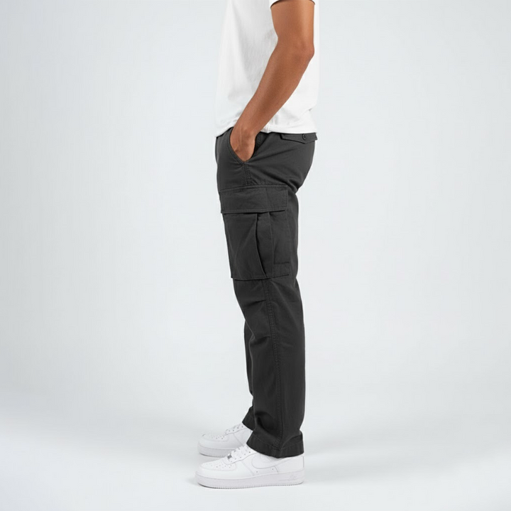Side profile of men's charcoal grey relaxed-fit cotton cargo trousers with side pockets and white sneakers.