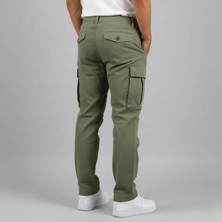 Olive green relaxed-fit men's cargo trousers with side pockets and buttoned back pockets, styled with white sneakers.