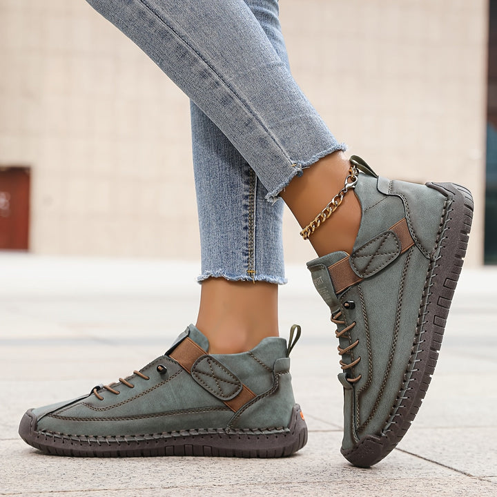 Grey Nora trainers featuring contrast stitching, lace-up front, and a secure hook-and-loop strap for a custom fit.
