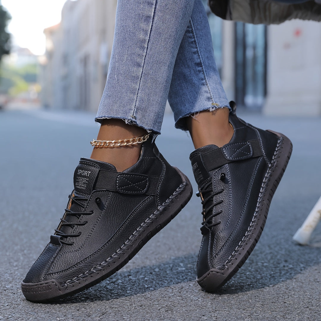 Black Nora trainers featuring contrast stitching, lace-up front, and a secure hook-and-loop strap for a stylish, custom fit.