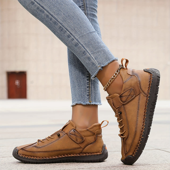 Tan leather Nora trainers featuring contrast stitching, a secure hook-and-loop strap, and a durable treaded sole.