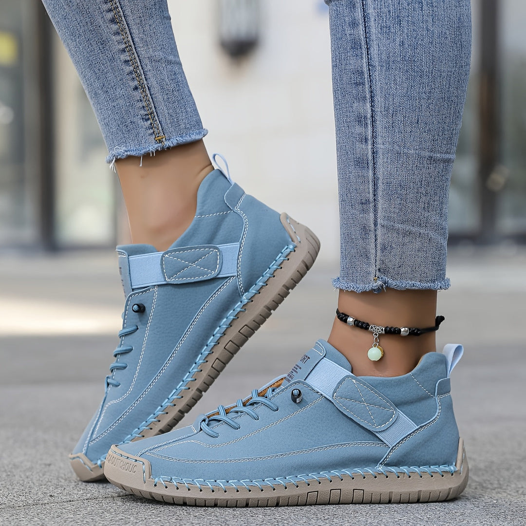 Blue Nora trainers featuring a lace-up front, secure hook-and-loop strap, contrast stitching, and a comfortable flat rubber sole.