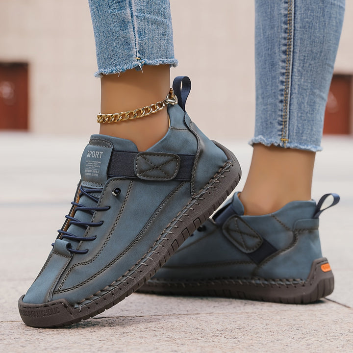 Blue Nora trainers featuring a lace-up front, secure hook-and-loop strap, contrast stitching, and a comfortable flat sole.