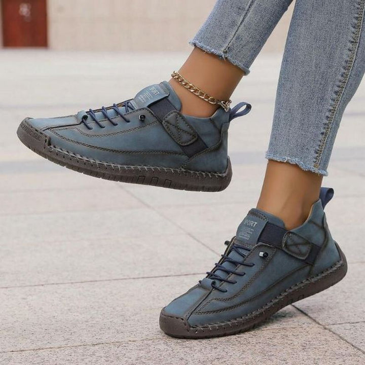 Blue Nora trainers featuring a lace-up front, hook-and-loop strap, contrast stitching, and a durable treaded flat sole.