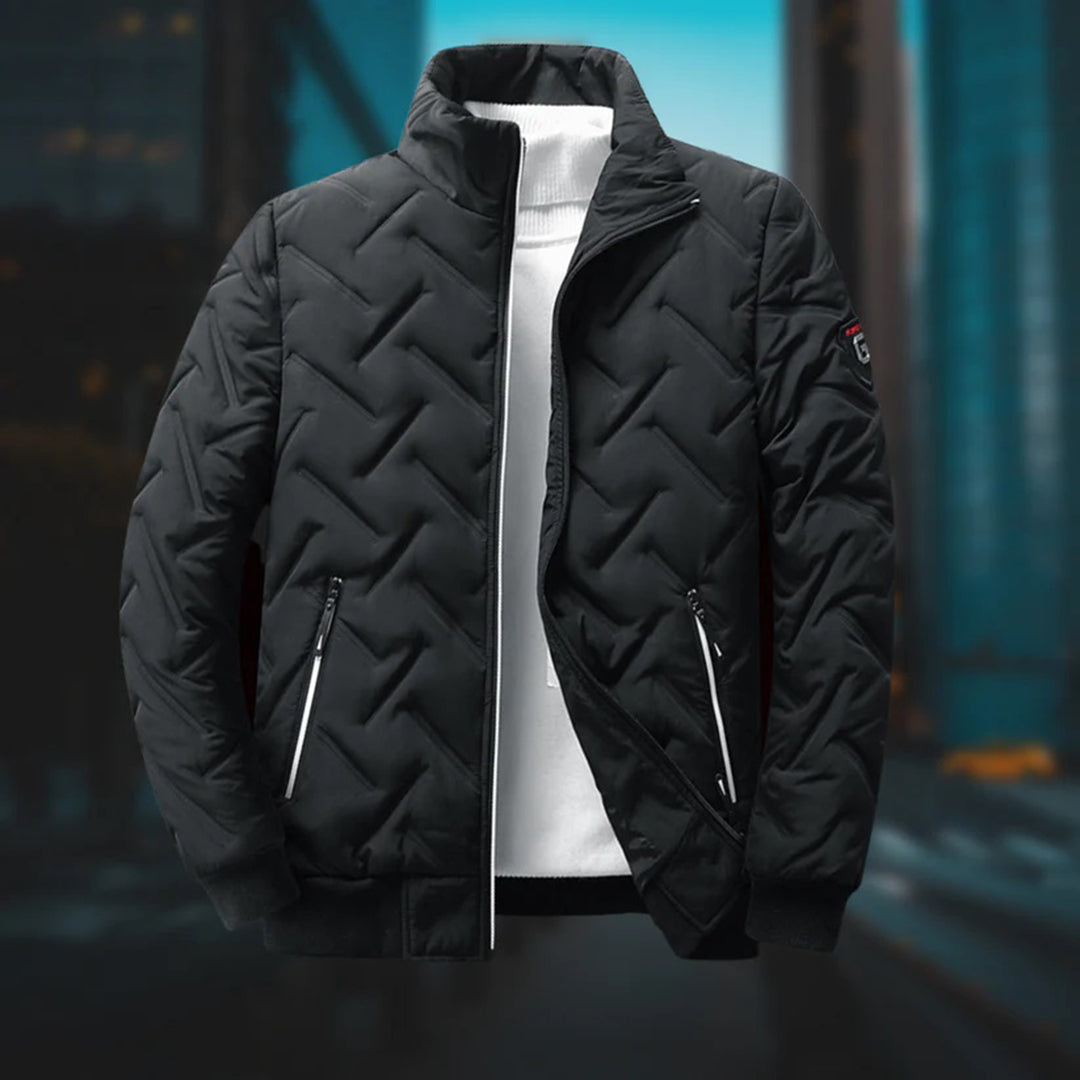 Black men's quilted chevron padded jacket with a stand-up collar, zip pockets, and ribbed hem over a white sweater.