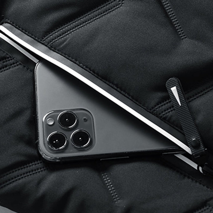 Close-up of a black quilted men's jacket featuring a secure zip pocket holding a smartphone.