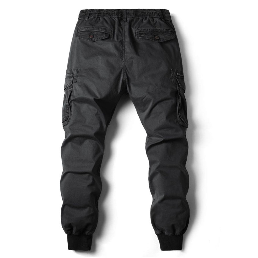 Black cotton utility cargo trousers with an elasticated drawstring waist, side cargo pockets, and cuffed ankles.