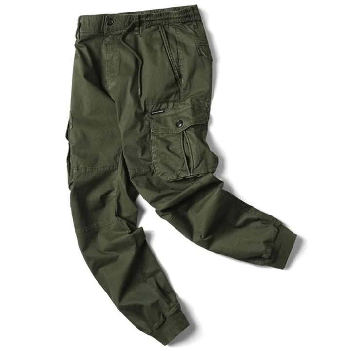 Olive green cotton utility cargo trousers with an elasticated drawstring waist, side flap pockets, and cuffed ankles.