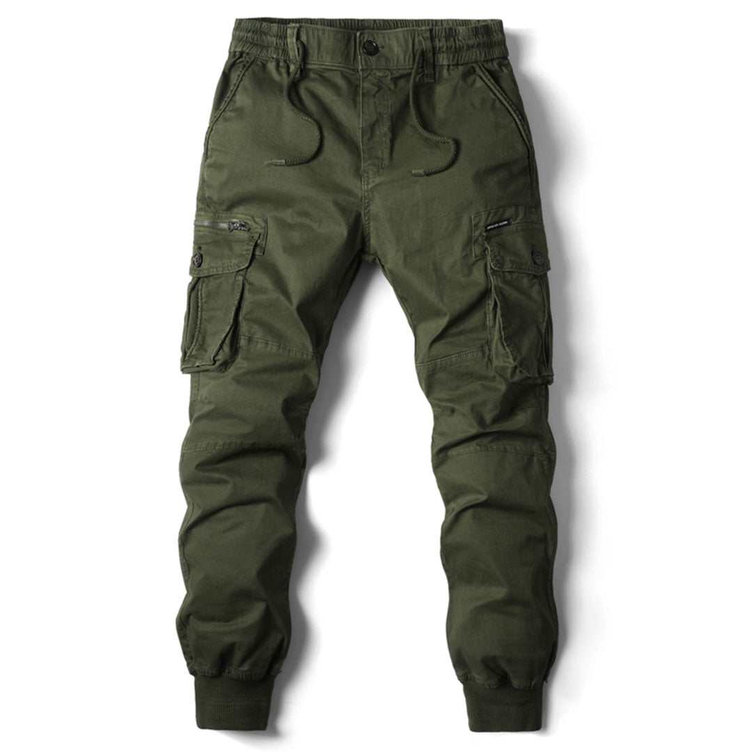 Olive green cotton cargo trousers with a drawstring waist, multiple utility pockets, and cuffed ankles on a white background.