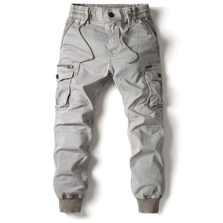 Grey cotton utility cargo trousers with an elasticated drawstring waist, multiple side pockets, and cuffed ankles.