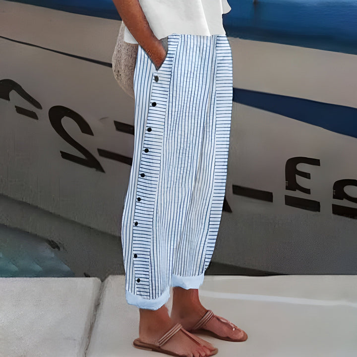 Women's Penny relaxed linen trousers in white with thin blue stripes, featuring side buttons and an elastic waistband.