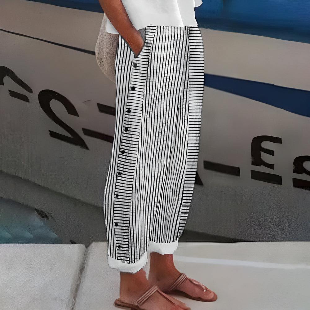 Women's Penny relaxed linen trousers in white with black vertical stripes and side buttons, perfect for travel.
