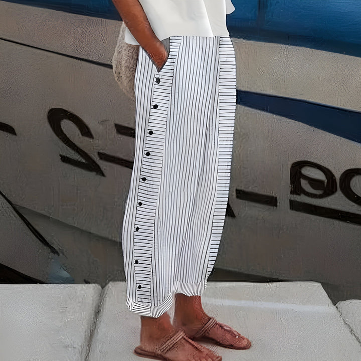 Women's Penny relaxed linen trousers in white with black vertical stripes and side buttons, perfect for warm days.